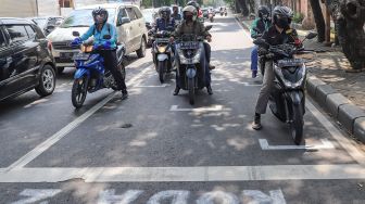 Pengendara motor berhenti pada garis pembatas antar pengendara di Jalan Hang Tuah Raya, Jakarta Selatan, Selasa, (16/6). [Suara.com/Alfian Winanto]