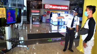 Petugas keamanan memeriksa suhu tubuh pengunjung melalui layar saat pembukaan kembali pusat perbelanjaan Mall BTM, Kota Bogor, Jawa Barat, Kamis (18/6/2020).  [ANTARA FOTO/Arif Firmansyah]
