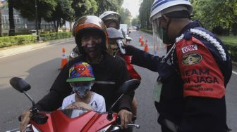 Petugas memeriksa suhu tubuh pengunjung sebelum memasuki komplek Gelora Bung Karno, Jakarta, Kamis (18/6). [Suara.com/Angga Budhiyanto]
