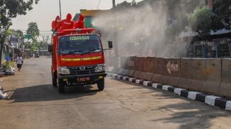 Petugas menyemprotkan disinfektan dengan truk Damkar di area Pasar Minggu, Jakarta Selatan, Sabtu (20/6). [Suara.com/Alfian Winanto]
