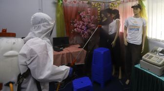 Petugas Palang Merah Indonesia (PMI) Jakarta Pusat menyemprotkan cairan disinfektan di lingkungan Sekolah Menengah Kejuruan Negeri (SMKN) 19, Bendungan Hilir Jakarta Pusat, Senin (22/6). [Suara.com/Angga Budhiyanto]    