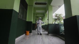 Petugas Palang Merah Indonesia (PMI) Jakarta Pusat menyemprotkan cairan disinfektan di lingkungan Sekolah Menengah Kejuruan Negeri (SMKN) 19, Bendungan Hilir Jakarta Pusat, Senin (22/6). [Suara.com/Angga Budhiyanto]    