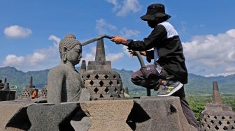 Petugas Balai Konservasi Borobudur (BKB) menyemprotkan air saat membersihkan abu vulkanik erupsi gunung Merapi di Candi Borobudur, Magelang, Jawa Tengah, Senin(22/6/2020).   [ANTARA FOTO/Anis Efizudin]
