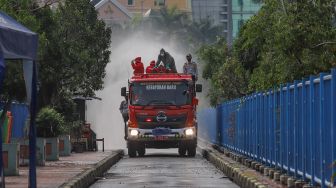 Petugas melakukan penyemprotan disinfektan di area Terminal Blok M, Jakarta Selatan, Selasa (23/6).  [Suara.com/Alfian Winanto]