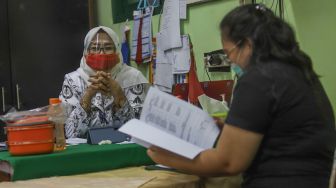 Orang tua murid mengecek rapor anaknya di SDN 01 Menteng, Jakarta Pusat, Kamis (25/6). [Suara.com/Alfian Winanto]