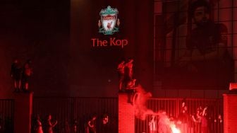 Suporter merayakan keberhasilan Liverpool menjadi juara Liga Inggris 2019/2020 di luar Anfield di Liverpool, Inggris, 25 Juni 2020.  [Oli SCARFF / AFP]