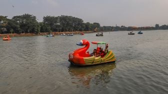 Warga menaiki wahana sepeda air di Setu Babakan, Jakarta Selatan, Sabtu (27/6). [Suara.com/Alfian Winanto]
