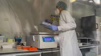 Petugas medis meneliti sampel spesimen didalam laboratoriun kontainer Covid-19 di RSKD Duren Sawit, Jakarta Timur, Sabtu (27/6). [Suara.com/Alfian Winanto]