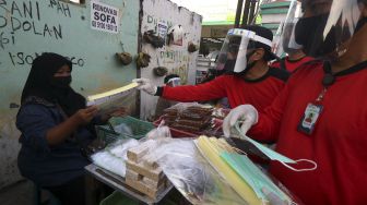 Satgas Kampung Tangguh membagikan alat pelindung wajah (face shield) kepada pedagang di Pasar Keputih, Surabaya, Jawa Timur, Minggu (28/6). [ANTARA FOTO/Didik Suhartono]