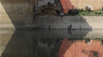 Jabar (40) mencari cacing sutra (Tubifex sp) di Banjir Kanal Timur (BKT) di kawasan pintu air WEIR-1 Malaka Sari, Jakarta, Selasa (30/6). [Suara.com/Angga Budhiyanto]