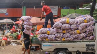 Pedagang menurunkan sayuran di Pasar Induk Kramat Jati, Jakarta Timur, Selasa (30/6). [Suara.com/Alfian Winanto]
