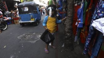 Bocah menggunakan kantong plastik saat berbelanja di Pasar Jatinegara, Jakarta, Selasa (30/6). [Suara.com/Angga Budhiyanto]