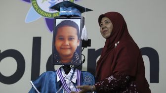 Kepala Sekolah berfoto bersama siswa Kelompok Bermain Taman Kanak-kanak (KB TK) saat wisuda virtual menggunakan Roboda (Robot Wisuda) di Sekolah Nasional Satu (Nassa School), Bekasi, Jawa Barat, Rabu (1/7). [Suara.com/Angga Budhiyanto]