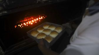 Pekerja mengeluarkan roti dari mesin pemanggang di rumah produksi roti di kawasan Bendungan Hilir, Jakarta, Jumat (3/7). [Suara.com/Angga Budhiyanto]