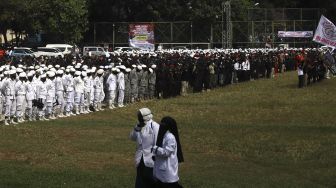 Dua massa melintas saat sejumlah massa dari berbagai elemen organisasi kemasyarakatan Islam menggelar 'Apel Siaga Ganyang Komunis' di Lapangan Ahmad Yani, Kebayoran Lama, Jakarta Selatan, Minggu (5/7). [Suara.com/Angga Budhiyanto]