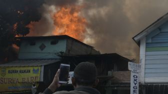 Warga mengambil gambar proses pemadaman api yang membakar sejumlah toko di Jalan Minangkabau Barat, Manggarai, Jakarta, Selasa (7/7/2020).  [ANTARA FOTO/Galih Pradipta]
