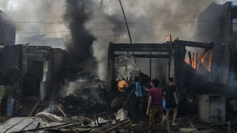 Warga berusaha memadamkan api yang membakar sejumlah toko di Jalan Minangkabau Barat, Manggarai, Jakarta, Selasa (7/7/2020).  [ANTARA FOTO/Galih Pradipta]