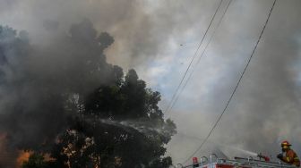 Petugas pemadam kebakaran bersama warga berusaha memadamkan api yang membakar sejumlah toko di Jalan Minangkabau Barat, Manggarai, Jakarta, Selasa (7/7/2020).  [ANTARA FOTO/Galih Pradipta]