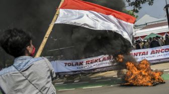 Mahasiswa yang tergabung dalam Gerakan Nasional Tolak Reklamasi (Gentar) Jakarta mengibarkan bendera merah putih saat melakukan aksi unjuk rasa di depan gedung Balai Kota, Jakarta, Rabu (8/7/2020).  [ANTARA FOTO/Galih Pradipta]