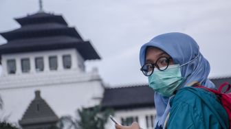 Warga mengenakan masker saat beraktivitas di depan Gedung Sate, Bandung, Jawa Barat, Kamis (9/7/2020).  [ANTARA FOTO/Novrian Arbi]