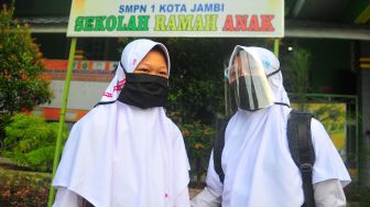 Siswi kelas VII SMPN 1 Kota Jambi mengenakan masker dan pelindung wajah sebelum memasuki kelas pada hari pertama sekolah Tahun Pelajaran 2020/2021 di Jambi, Senin (13/7/2020). [Foto/Antara]