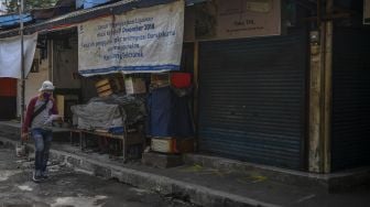 Warga berjalan di depan toko yang tutup di Pasar Cempaka Putih, Jakarta, Senin (13/7/2020).  [ANTARA FOTO/Nova Wahyudi]