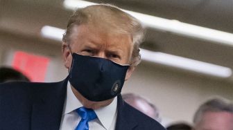 Presiden Amerika Serikat Donald Trump mengenakan masker saat menyusuri lorong dalam kunjunganya ke Pusat Kesehatan Militer Nasional Walter Reed di kawasan Washington, Amerika Serikat.  [ALEX EDELMAN / AFP]