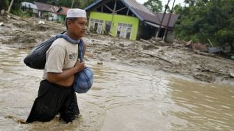 Warga berusaha menerobos banjir di Desa Radda, Kabupaten Luwu Utara, Sulawesi Selatan, Selasa (14/7/2020). [ANTARA FOTO/Hariandi Hafid]
