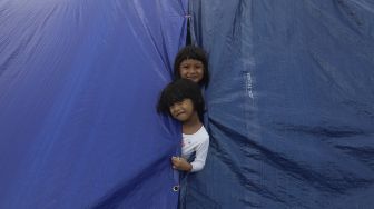 Dua anak warga Kampung Muka bermain di tenda darurat yang didirikan secara mandiri setelah penggusuran pada 15 Juli 2020 lalu di Kawasan Stasiun Kampung Bandan, Jakarta, Jumat (17/7/2020). [Suara.com/Angga Budhiyanto]