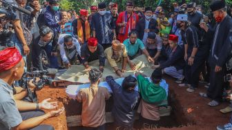 Proses penurunan jenazah komedian Omaswati ke liang lahat di TPU Cisalak, Cimanggis, Depok, Jawa Barat, Jumat (17/7). [Suara.com/Alfian Winanto]