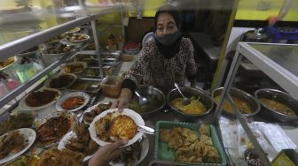 Pemilik warteg melayani pembeli di warteg yang menerapkan protokol kesehatan di kawasan Cilandak Timur, Jakarta Selatan, Senin (20/7/2020). [Suara.com/Angga Budhiyanto]