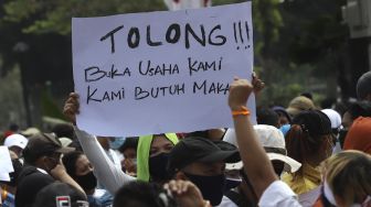 Massa yang tergabung dalam Asosiasi Pengusaha Hiburan Jakarta (Asphija) membentangkan poster saat melakukan aksi unjuk rasa di depan Balai Kota DKI Jakarta, Selasa (21/7/2020). [Suara.com/Angga Budhiyanto] 