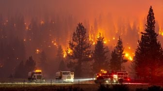 Sejumlah kendaraan menjauh saat api mulai menyambar dan membakar hutan di seberang jalan sekitar 5 mil dari Susanville, California, Amerika Serikat, Senin (20/7/2020).    [AFP/JOSH EDELSON]