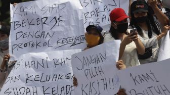 Sejumlah massa yang tergabung dalam Asosiasi Pengusaha Hiburan Jakarta (Asphija) membentangkan poster saat melakukan aksi unjuk rasa di depan Balai Kota DKI Jakarta, Selasa (21/7/2020). [Suara.com/Angga Budhiyanto] 