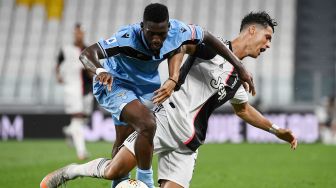 Pemain depan Lazio Bobby Adekanye (kiri) mencoba merebut bola dengan pemain depan Juventus Cristiano Ronaldo selama pertandingan sepak bola Serie A Italia antara Juventus melawan Lazio di Stadion Allianz, di Turin, Italia, Selasa (21/7) dini hari WIB. [Marco BERTORELLO / AFP]