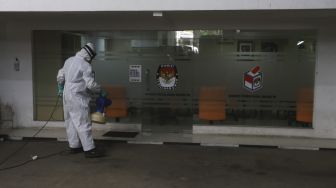 Petugas menyemprotkan cairan disinfektan di gedung Komisi Pemilihan Umum (KPU) Republik Indonesia, Jakarta, Selasa (21/7/2020). [Suara.com/Angga Budhiyanto]