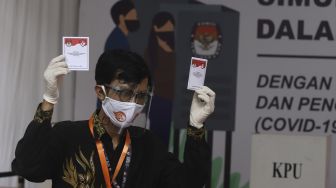 Seorang petugas menunjukkan surat suara saat simulasi pemungutan suara Pilkada Serentak 2020 di Kantor Komisi Pemilihan Umum (KPU) Republik Indonesia, Jakarta, Rabu (22/72020). [Suara.com/Angga Budhiyanto]