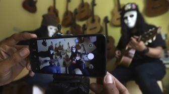 Pemilik toko dan bengkel kerja 'Music666' memainkan gitar yang akan dijual secara online di Ciledug, Tangerang, Banten, Rabu (22/7/2020). [Suara.com/Angga Budhiyanto]