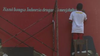 Pekerja menyelesaikan mural bertemakan Proklamasi di Sekolah Dasar Negeri (SDN) Pondok Aren 02, Tangerang Selatan, Banten, Rabu (22/7/2020). [Suara.com/Angga Budhiyanto]