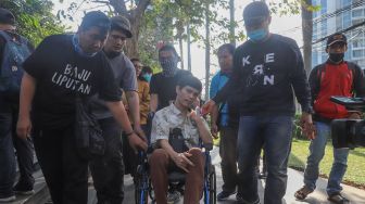 Rekan - rekan media membantu mendorong kursi roda El Ibnu vokalis band Elkasih saat ditemui di Kawasan Tandean, Jakarta Selatan, Rabu (22/7). [Suara.com/Alfian Winanto]