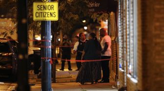 Polisi mengintrograsi warga saat menyelidiki lokasi penembakan di Chicago, Illinois, Amerika Serikat,  Selasa (21/7). [KAMIL KRZACZYNSKI / AFP]