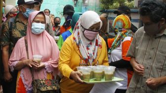Warga membagikan minuman kacang hijau pada pasien COVID-19 yang dinyatakan sembuh, Sukati (kiri) dan Hartoyo (kanan) di Kiduldalem, Malang, Jawa Timur, Rabu (22/7/2020).   [ANTARA FOTO/Ari Bowo Sucipto]