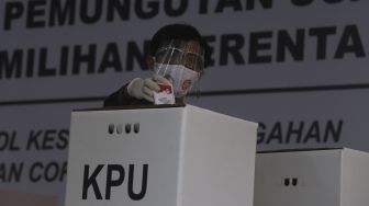 Seorang petugas memasukkan surat suara ke dalam kotak suara saat simulasi pemungutan suara Pilkada Serentak 2020 di Kantor Komisi Pemilihan Umum (KPU) Republik Indonesia, Jakarta, Rabu (22/72020). [Suara.com/Angga Budhiyanto]