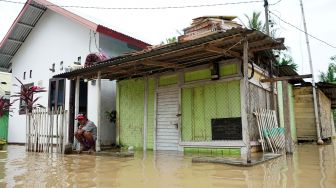 Seorang warga duduk di depan rumahnya yang terendam air luapan Sungai Bone di Ipilo, Kota Gorontalo, Gorontalo, Jumat (24/7/2020). [ANTARA FOTO/Adiwinata Solihin]
