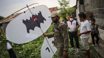 Petugas Satpol PP menyita layangan yang diterbangkan warga saat razia layangan di kawasan keselamatan operasi penerbangan Bandara Internasional Soekarno Hatta, Neglasari, Kota Tangerang, Banten, Sabtu (25/7/2020). [ANTARA FOTO/Fauzan]