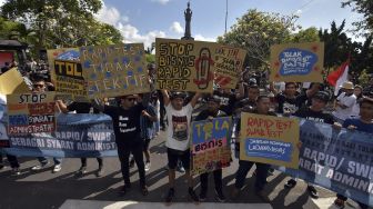 Puluhan pengunjuk rasa memajang tulisan dalam aksi menolak "rapid test" dan "swab test" COVID-19 di Denpasar, Bali, Minggu (26/7/2020). [ANTARA FOTO/Nyoman Hendra Wibowo]