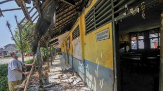 Petugas kebersihan mengamati bagian atap bangunan SDN Mekarsari 05 yang rusak di Tambun, Kabupaten Bekasi, Jawa Barat, Senin (27/7/2020). [ANTARA FOTO/Fakhri Hermansyah]