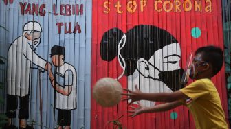 Seorang anak bermain di depan mural bertema COVID-19 di Jakarta, Senin (27/7/2020).  [ANTARA FOTO/Akbar Nugroho Gumay]