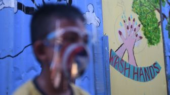 Seorang anak melintasi mural bertema COVID-19 di Jakarta, Senin (27/7/2020). [ANTARA FOTO/Akbar Nugroho Gumay]