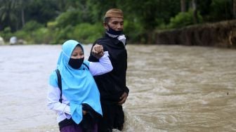 Dua orang guru Sekolah Dasar Negeri (SDN) 6 Tapa melintasi sungai Polanggua untuk mengajar pelajaran luar jaringan (luring) di Dusun III, Desa Langge, Tapa, Kabupaten Bone Bolango, Gorontalo, Rabu (29/7/2020). [ANTARA FOTO/Adiwinata Solihin]
